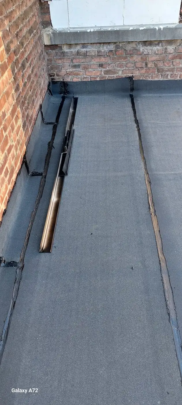 Toiture plate en roofing bitumé contre un mur de briques, étanchéité.
