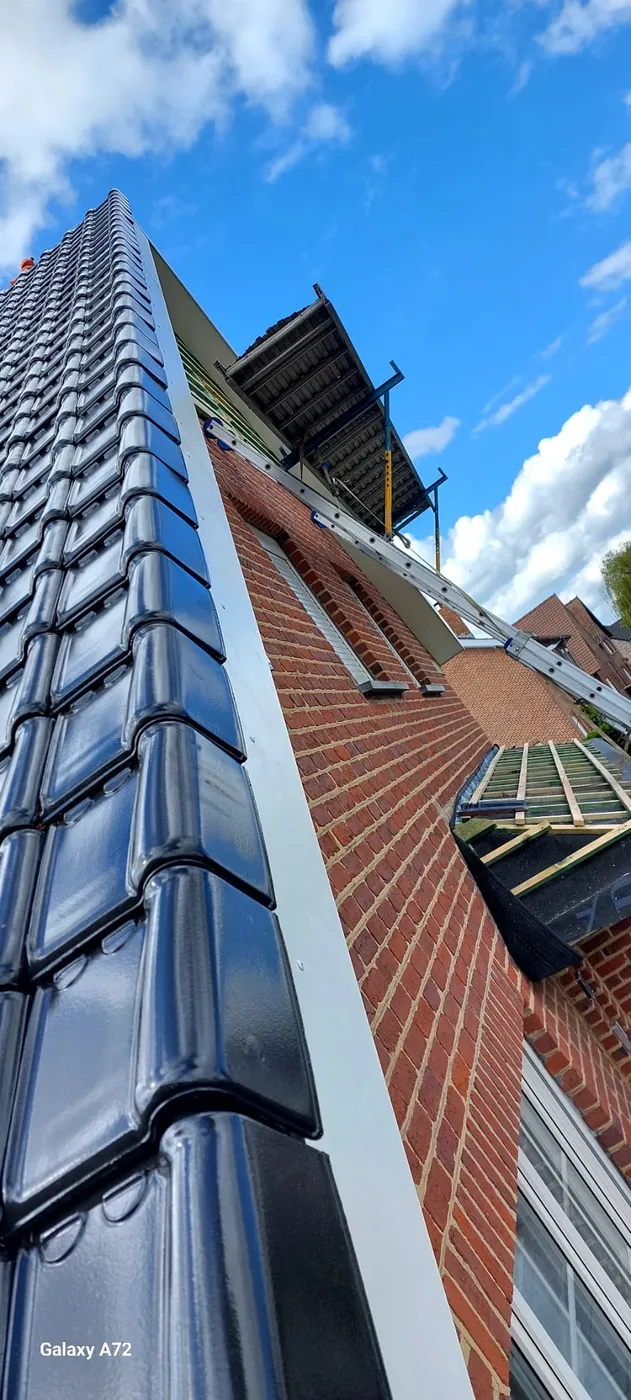 Toiture en tuiles noires avec échafaudage, chantier en cours.
