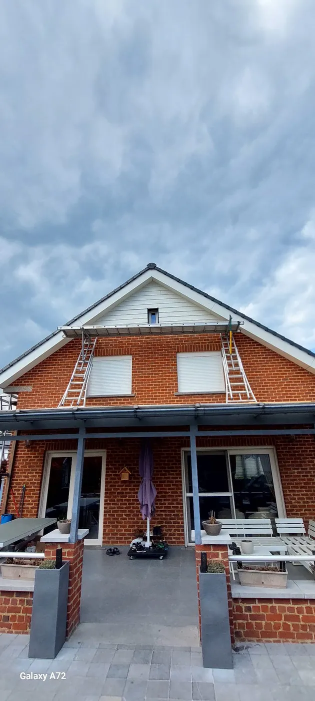 Façade en briques avec échelles, chantier de toiture sur le pignon.